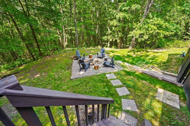 Make your way down, from the back deck, to the outdoor fire pit area surrounded by trees and the open sky.