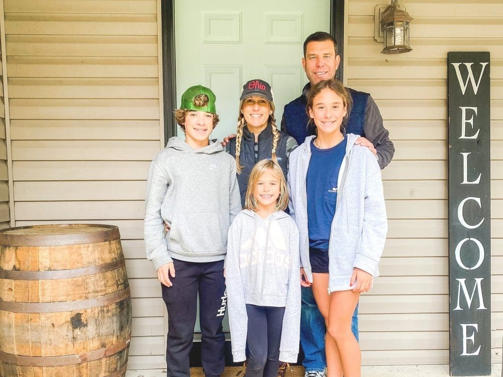 The Woodlands family standing outside their Hocking Hills cabin rental with a welcome sign