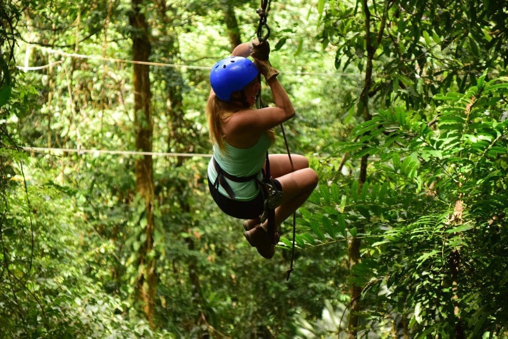 Woman ziplining between greenery.