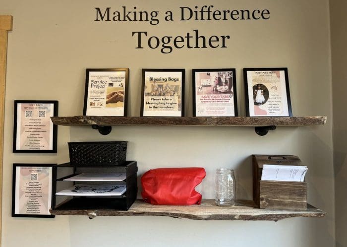 Wall shelf display with framed quotes, red bag, and volunteer information materials